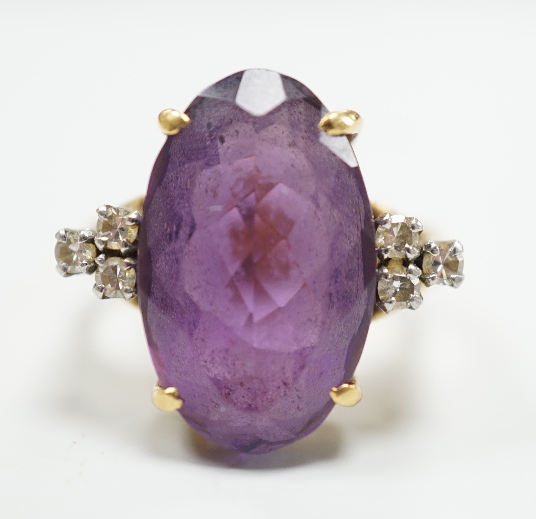A yellow metal and oval cut amethyst set dress ring, with six stone diamond set shoulders, size O, gross weight 9.6 grams.